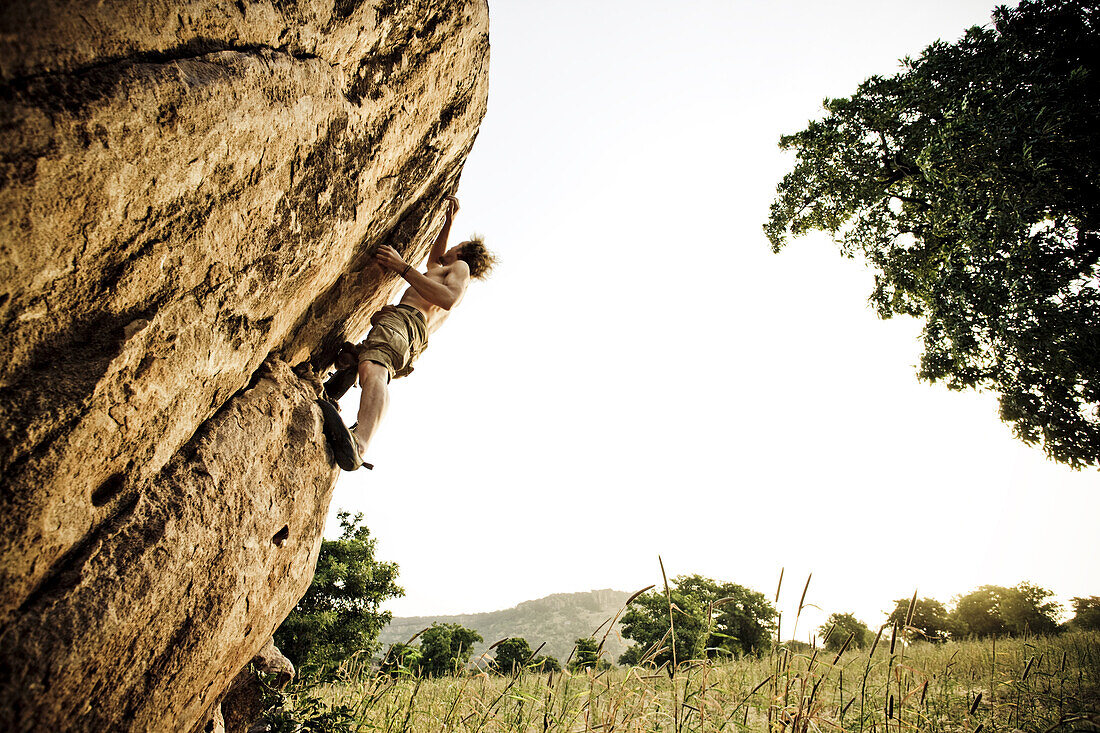 Young man bouldering in the morning sun, Mali, Africa