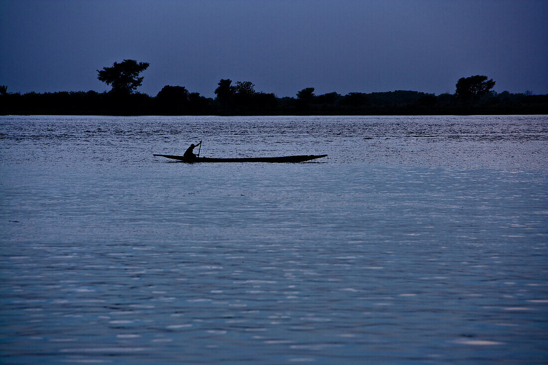 Mann paddelt abends mit Einbaum auf dem Niger, Sagou, Mali, Afrika