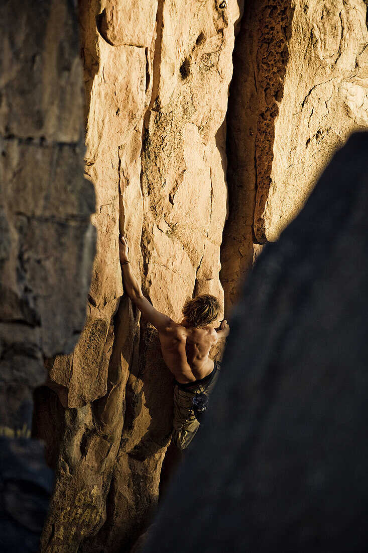 Young man bouldering in the evening sun, Hand of Fatima, Hombori, Mali, Africa