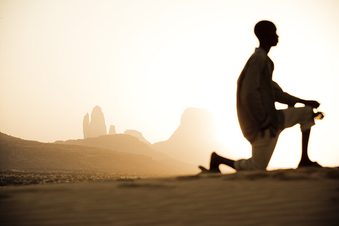 Kneeling boy in front of rock formation at sunset, Hombori, Mali, Africa