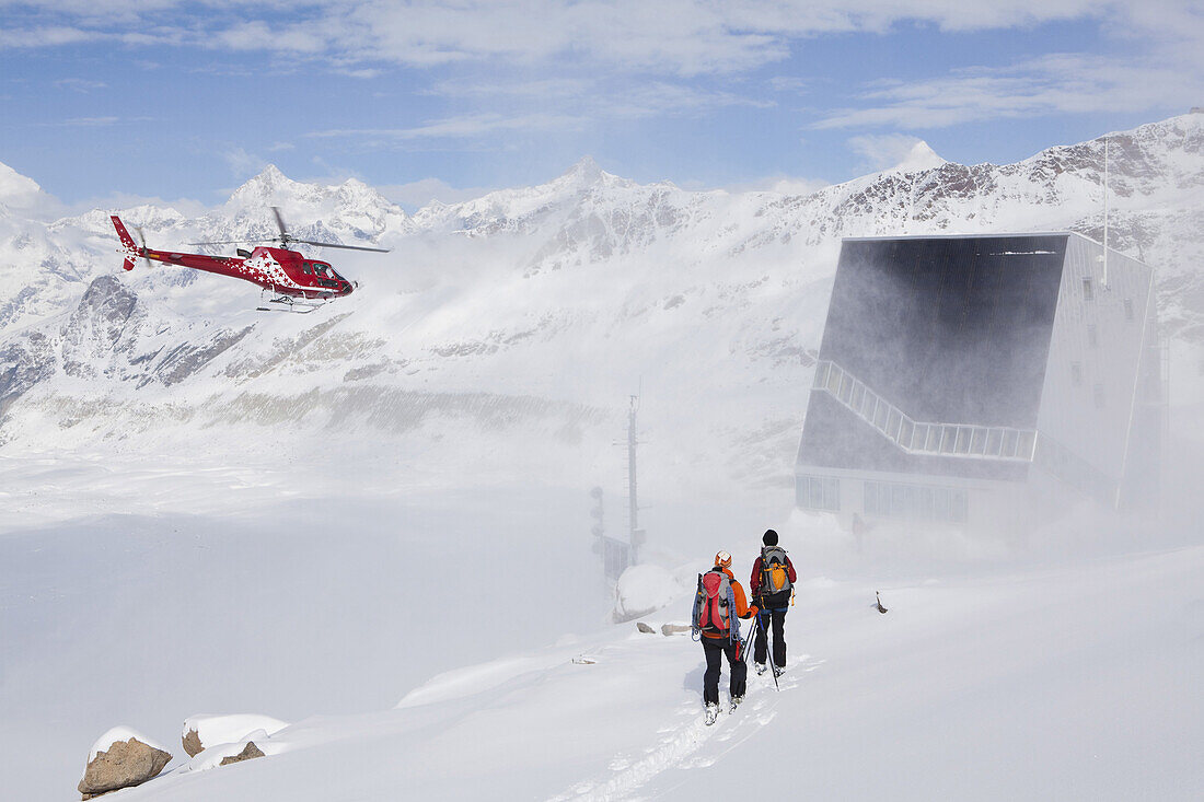 Two female back country skiers reaching Monte Rosa Hut, helicopter in background, Canton of Valais, Switzerland