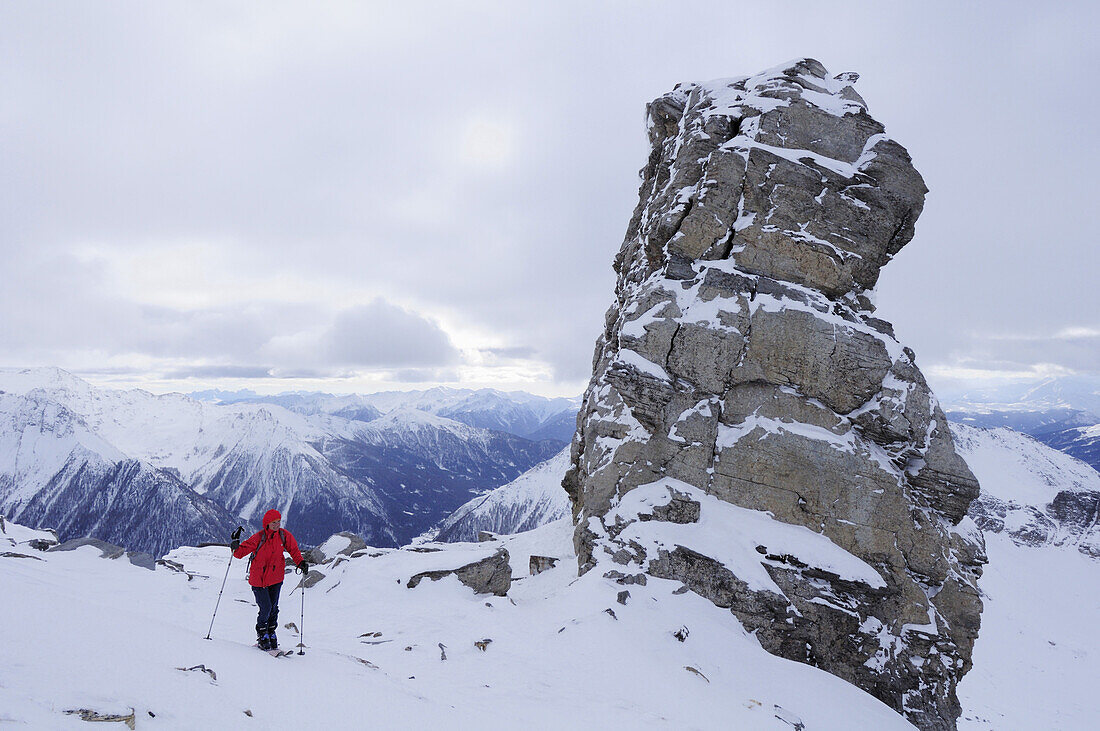 Frau auf Skitour geht an Felsturm vorüber, Wolfendorn, Tuxer Alpen, Südtirol, Italien