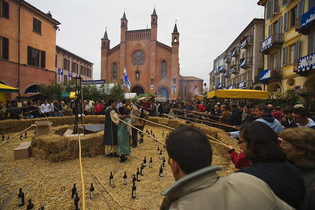 People fishing for wine bottles for a prize during the Palio di Alba festival, cathedral in the background, Piazza Risorgimento, Piedmont, Italy