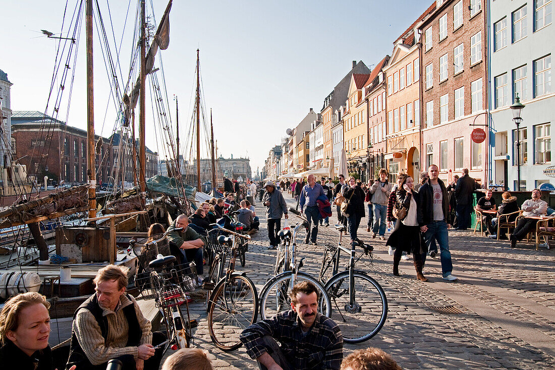 People sitting at along the waterfront of Nyhavn Canal, Copenhagen, Denmark