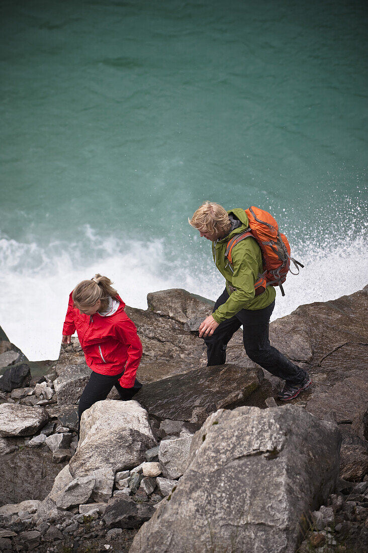 Paar wandert über Steine an einem See, Zillertal, Tirol, Österreich