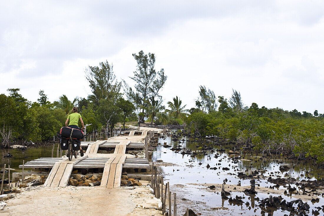 Mountainbikerin fährt über eine Holzbrücke, Nationalpark Masoala, Madagaskar