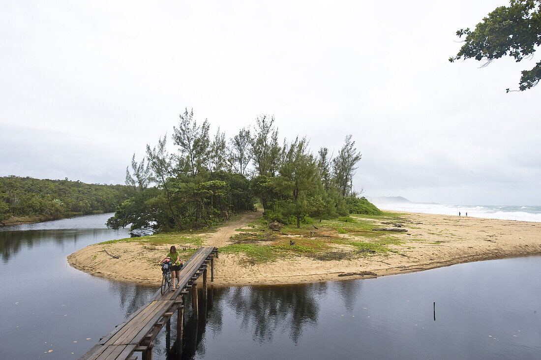 Woman pushing a mountainbike on a wooden bridge, Masoala National Park, Madagaskar