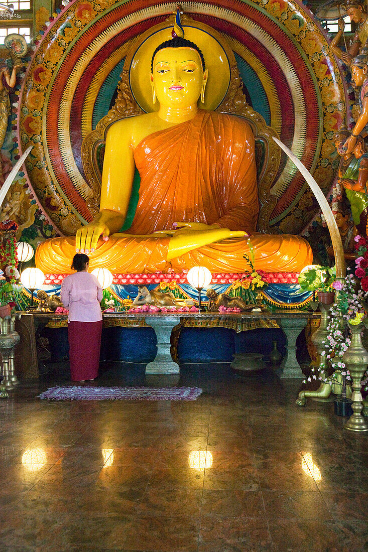 Frau vor einer grossen Buddhastatue im Gangaramaya Tempel, Colombo, Sri Lanka, Asien