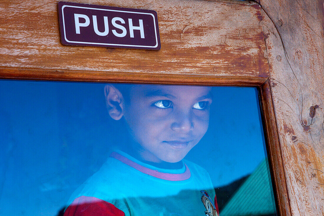 Little sinhalese boy behind the entrance door of the Grosvenor Hotel, Nuwara Eliya, Highland, Sri Lanka, Asia