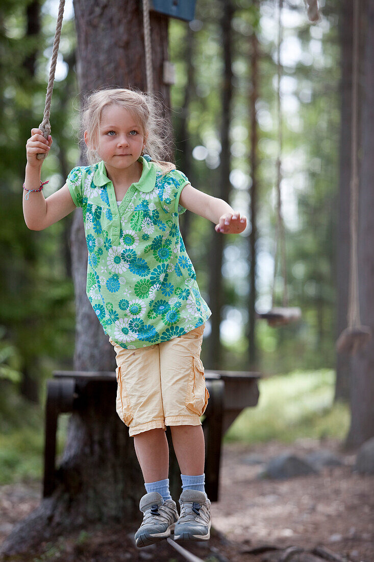 Ein Mädchen balanciert auf einem Kabel auf dem Abenteuerspielplatz der Insel Norrbyskär, Västerbotten, Schweden, Europa