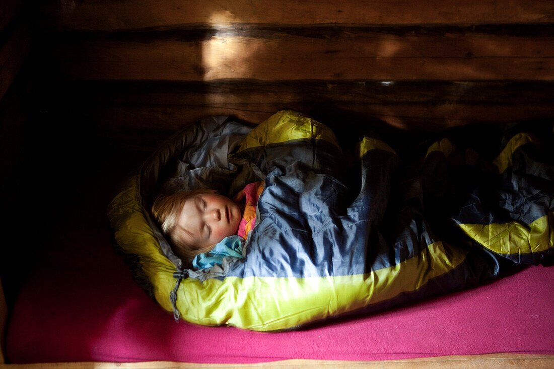 Girl sleeping in sleeping bag in a cottage, national park Skuleskogen, Höga Kusten, Vaesternorrland, Sweden, Europe