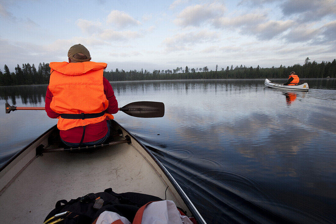 Two men in canoes on the lake of Trehörningsjö, Vaesternorrland, Sweden, Europe