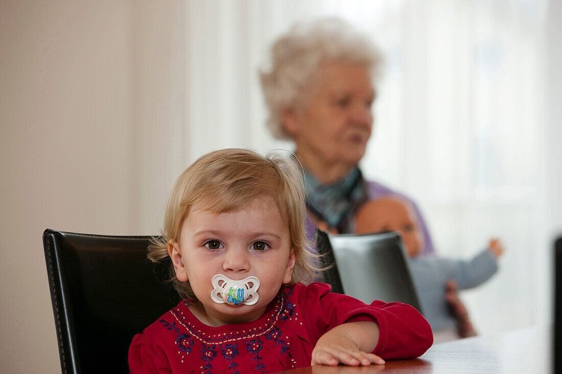 Girl (2 years), grandmother in background
