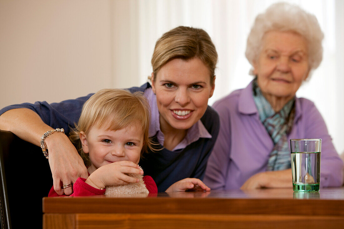 Girl (2 years), mother and grandmother sitting at a table