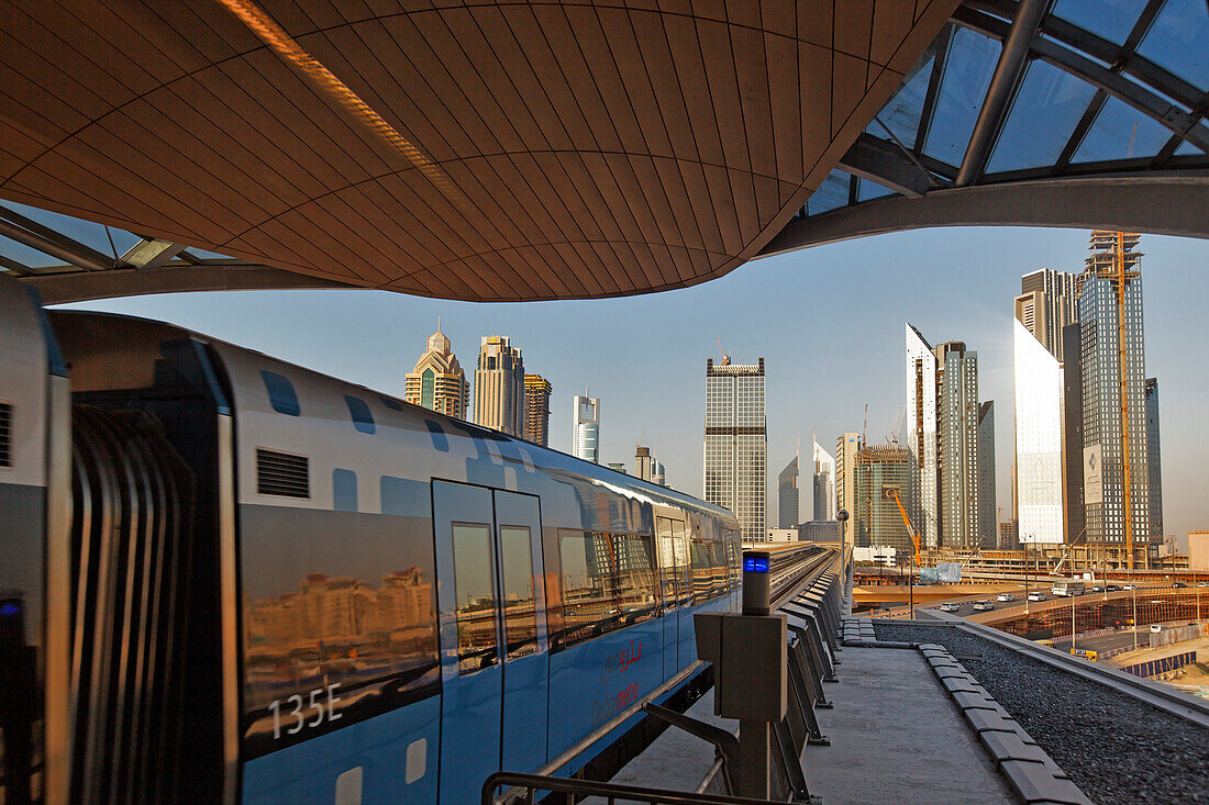 Neue Metro vor Skyline des Finanzzentrums von Dubai an der Zeihet Road