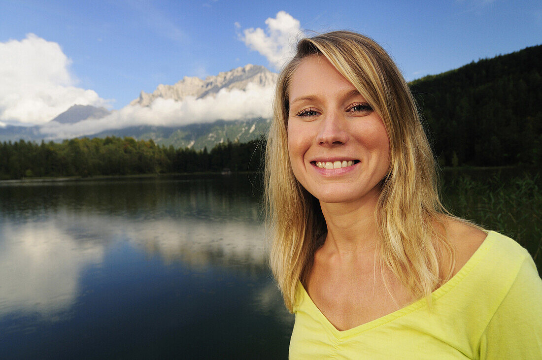 Young woman smiling at camera, lake Lautersee, Mittenwald, Werdenfelser Land, Upper Bavaria, Germany