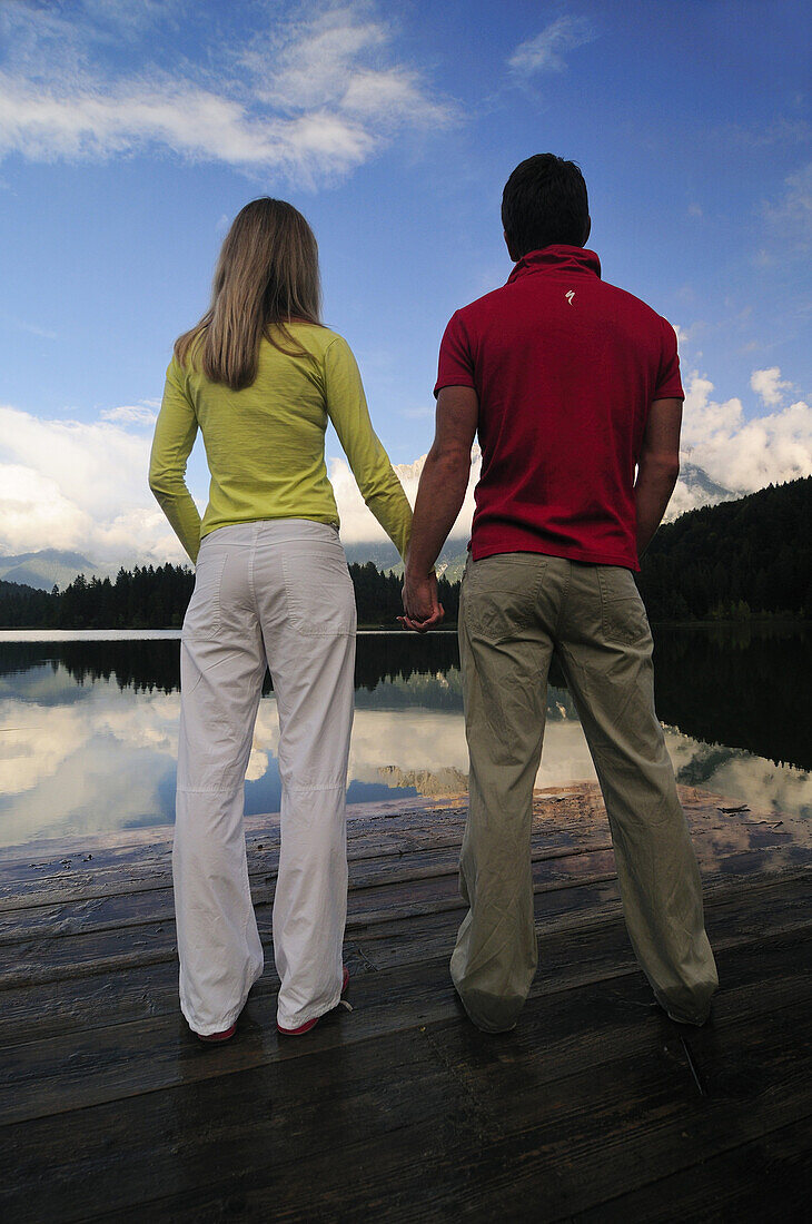 Couple holding hands on a jetty, lake Lautersee, Mittenwald, Werdenfelser Land, Upper Bavaria, Germany