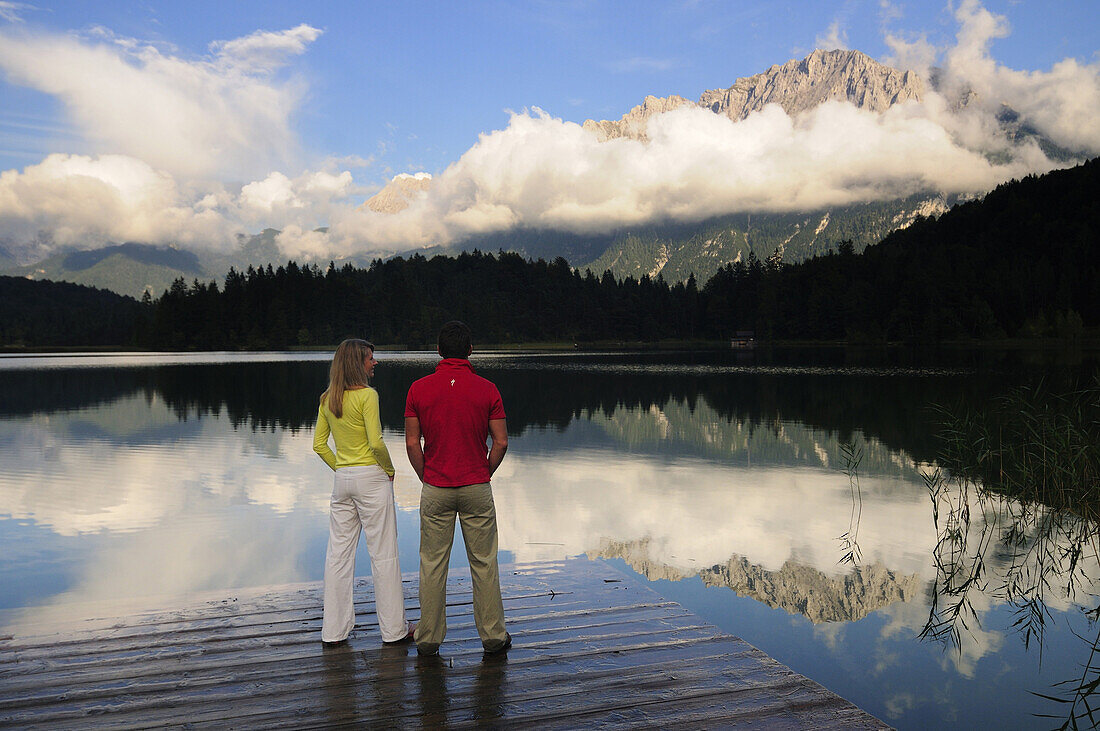 Couple standing on jetty, lake Lautersee, Mittenwald, Werdenfelser Land, Upper Bavaria, Germany