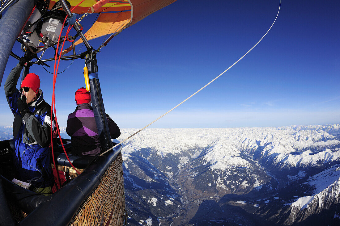 Two persons in hot-air balloon looking at snow covered alps, aerial photo, South Tyrol, Italy, Europe