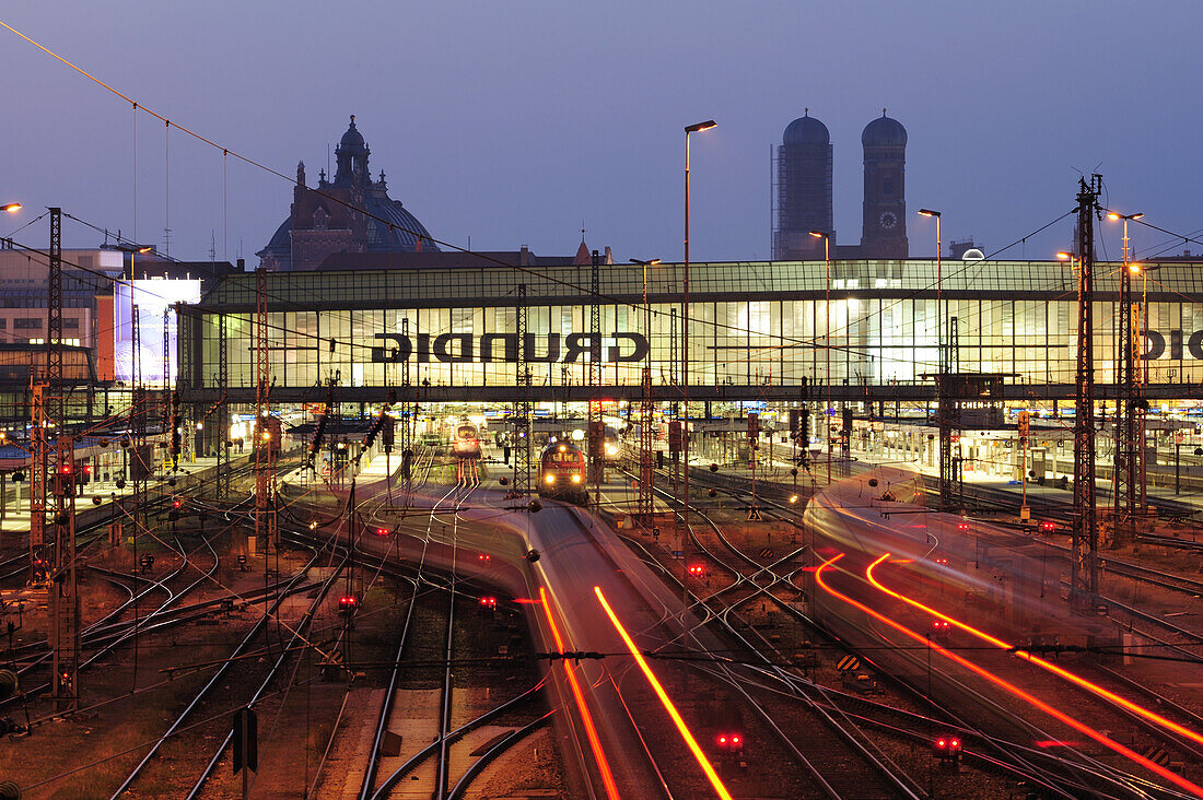 Illuminated tracks and railway building, twin towers of the Frauenkirche cathedral and palace of justice in the background, Munich main station, Munich, Upper Bavaria, Bavaria, Germany