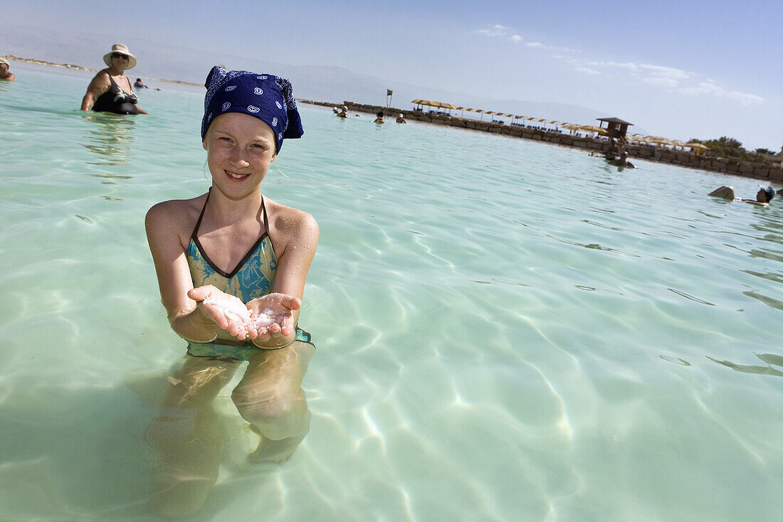 Mädchen steht im Toten Meer mit Meersalz in der Hand, En Bokek, Israel, Naher Osten