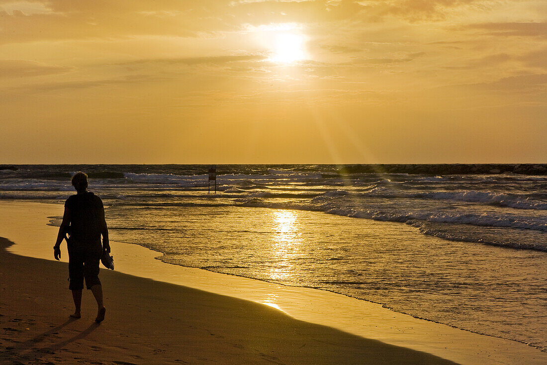 Eine Frau läuft bei Sonnenuntergang am Strand entlang, Gordon Beach, Tel Aviv, Israel, Naher Osten