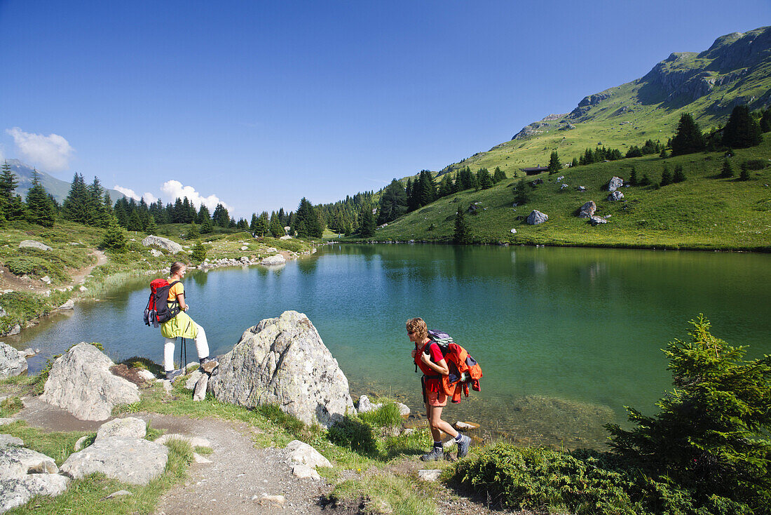 Zwei Frauen wandern an einem Bergsee, Alp Flix, Sur, Graubünden, Schweiz