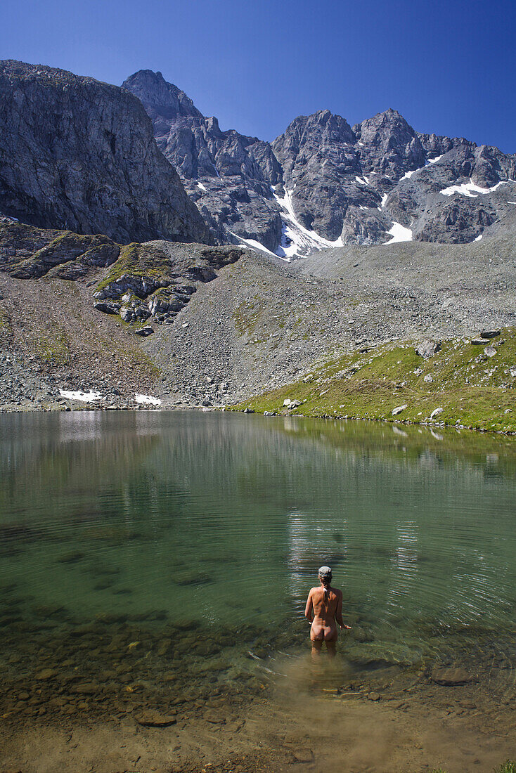 Naked woman bathing in lake Lai Neir, Val Bercla, Piz Platta in background, Canton of Grisons, Switzerland