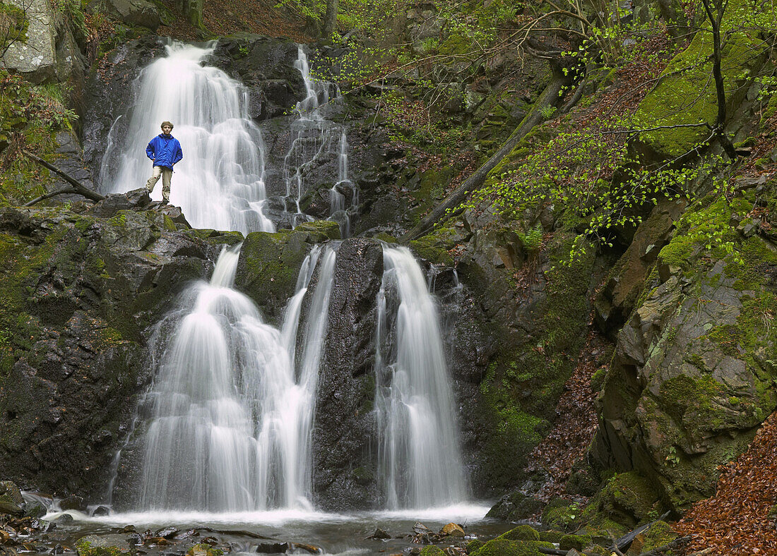 Boy standing next to waterfall