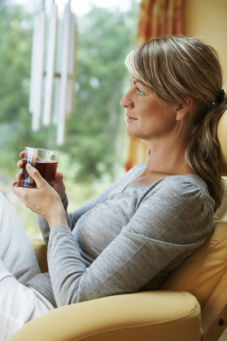 Woman relaxing in chair and is drinking tea
