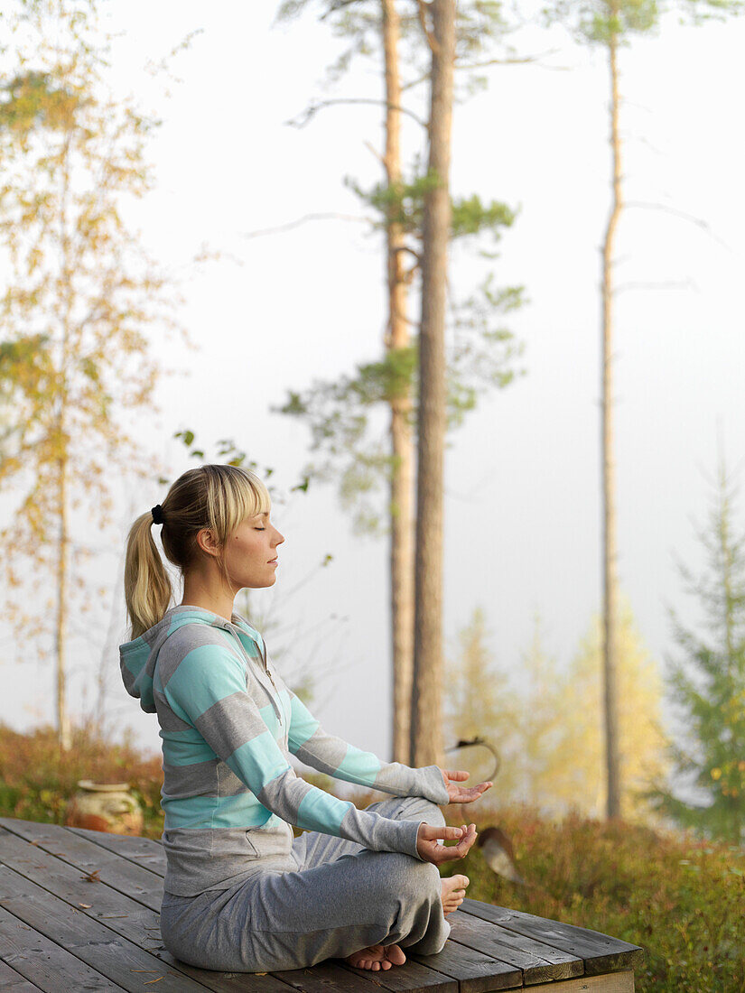 Woman meditates on terrace, Skane, Sweden