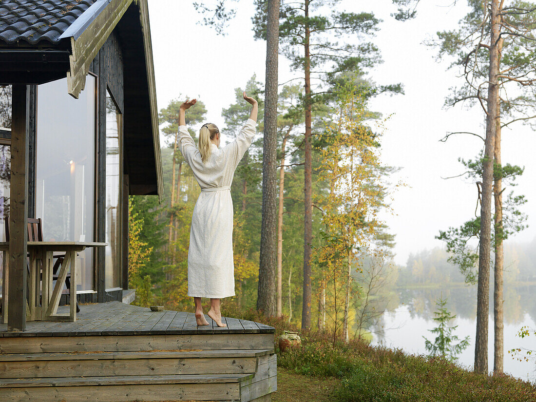 Woman in robe on terrace, Skåne, Sweden