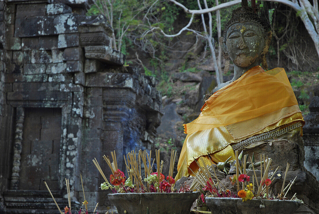 Sitzender Buddha mit gelbem Schal und Räuchrstäbchen im Wat Phu Champasak, Khmer Tempel, Champasak Provinz im Süden von Laos, Asien