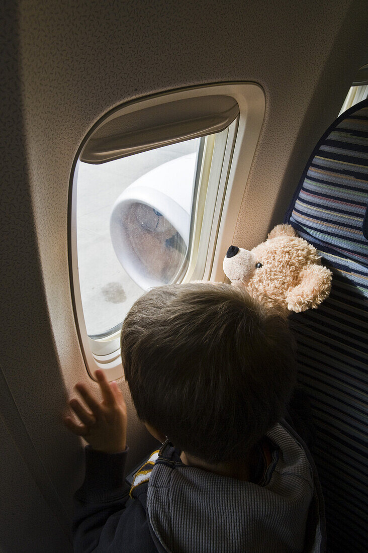 Junge blickt aus Fenster von einem Flugzeug, Flughafen München, Bayern, Deutschland
