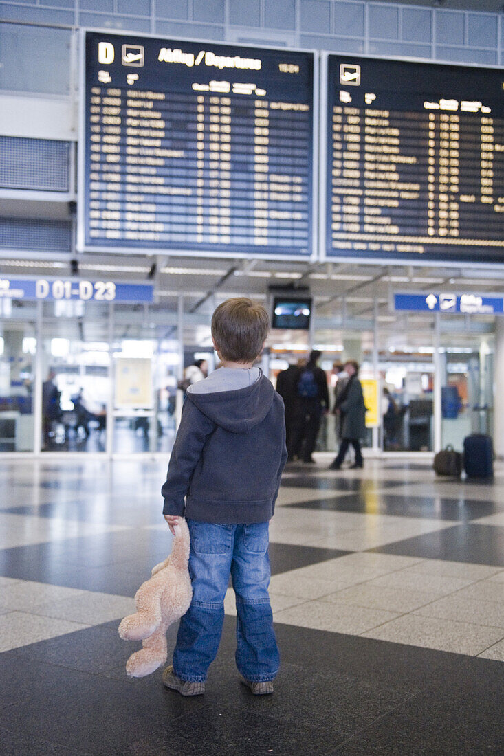 Junge mit Teddybär in Flughafenhalle, Flughafen München, Bayern, Deutschland