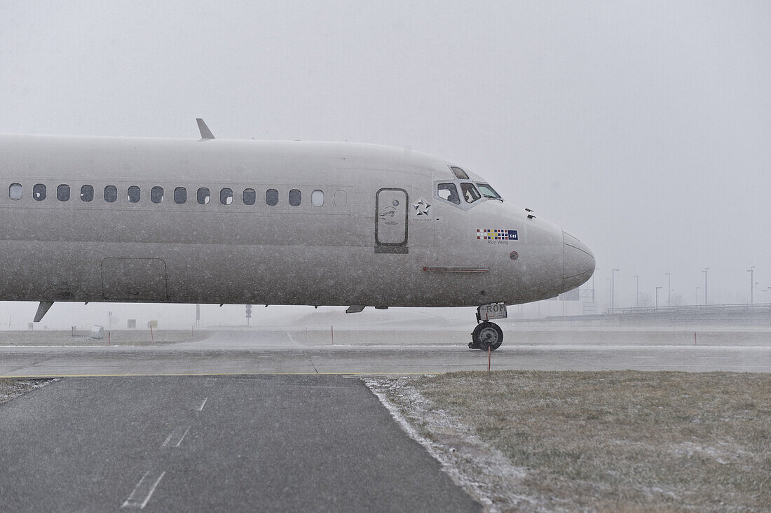 Airliner passing airport taxiway in snowfall, Munich airport, Bavaria, Germany