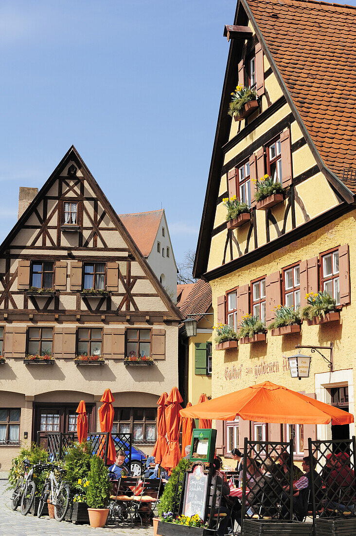 Guests sitting in the beer garden of a restaurant, half-timbered houses, Dinkelbuehl, Bavaria, Germany
