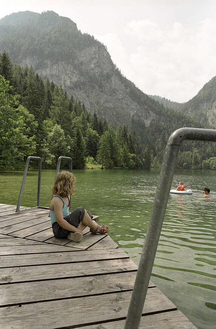 Junges Mädchen sitzt auf einem Holzsteg am Gleinkersee, Windischgarsten, Pyhrn-Priel, Oberösterreich, Österreich,  Alpen, Europa