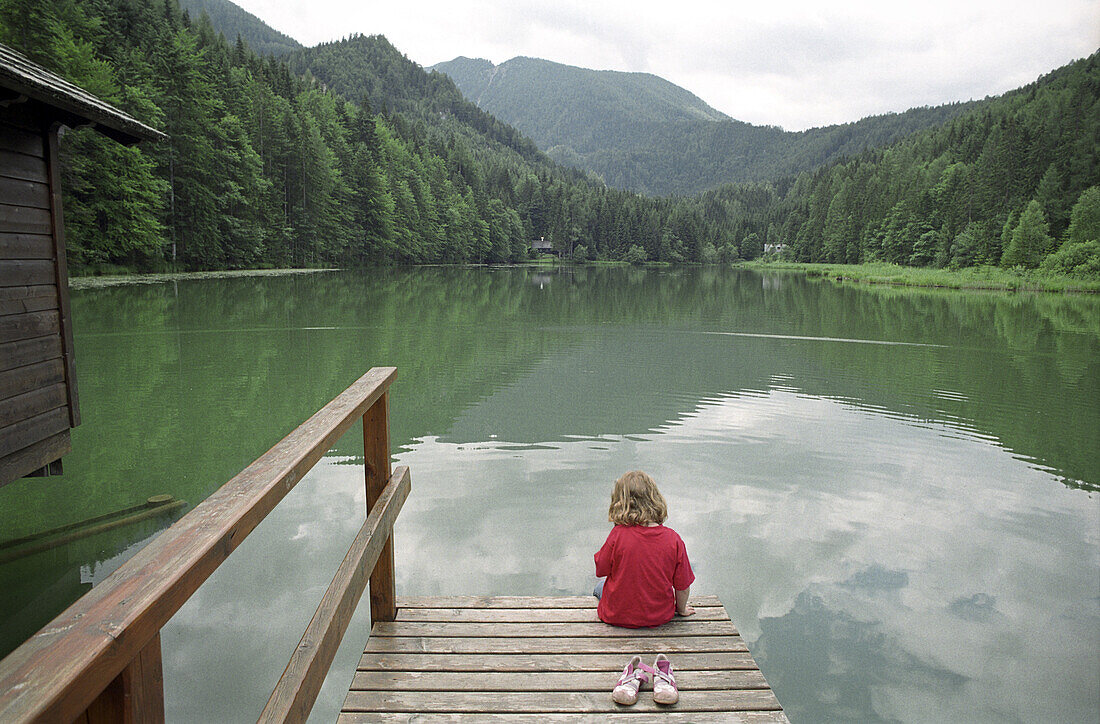 A little girl sitting by a lake, Schaffner Weiher, Stodertal, Austria, Alps, Europe