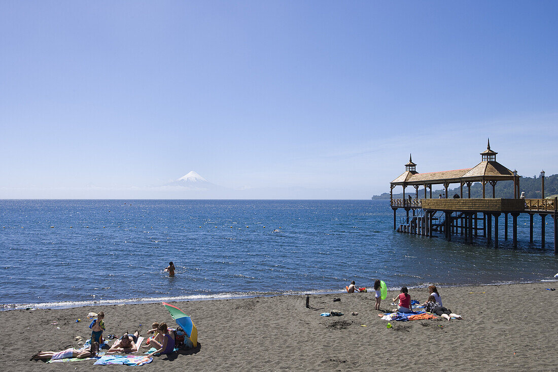 Menschen am Strand und Steg am Lago Llanquihue See mit Blick auf den Vulkan Osorno, Frutillar, Los Lagos, Patagonien, Chile, Südamerika, Amerika