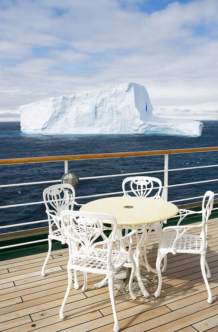 Tisch und Stühle an Deck von Kreuzfahrtschiff MS Deutschland (Reederei Deilmann) mit Blick auf antarktische Eisberge, Südliche Shetlandinseln, Antarktis