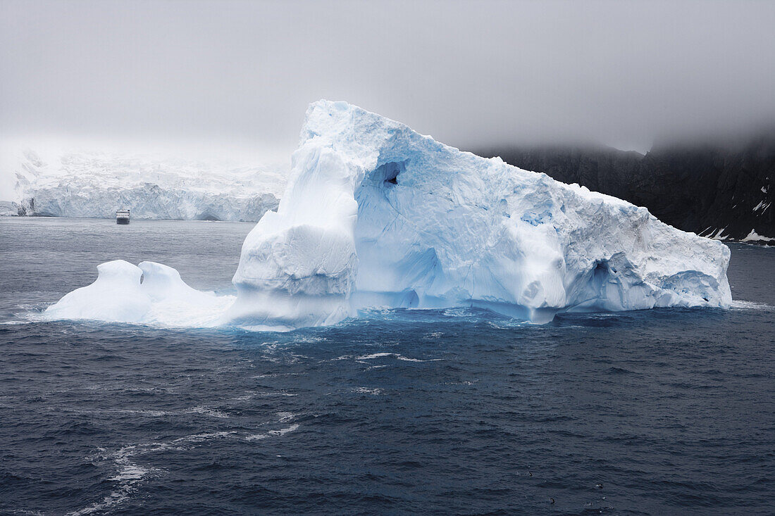Antarktischer Eisberg und Expeditionsschiff National Geographic Explorer, Südliche Shetlandinseln, Antarktis
