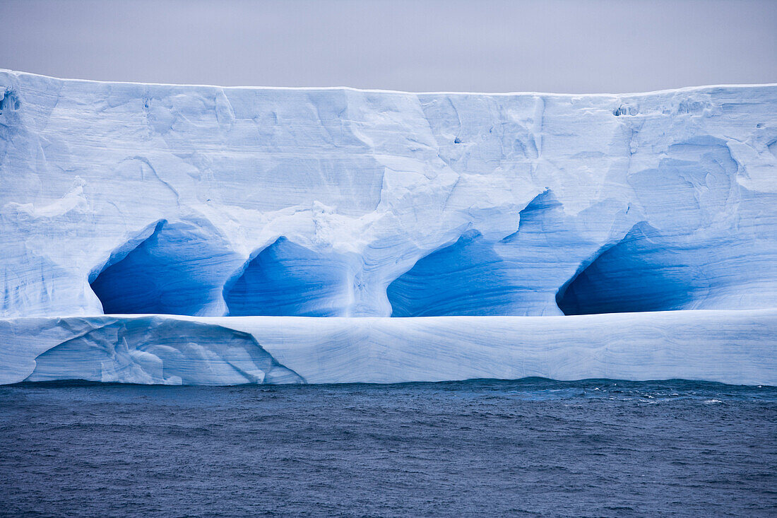 Blue Antarctic iceberg under clouded sky, South Shetland Islands, Antarctica