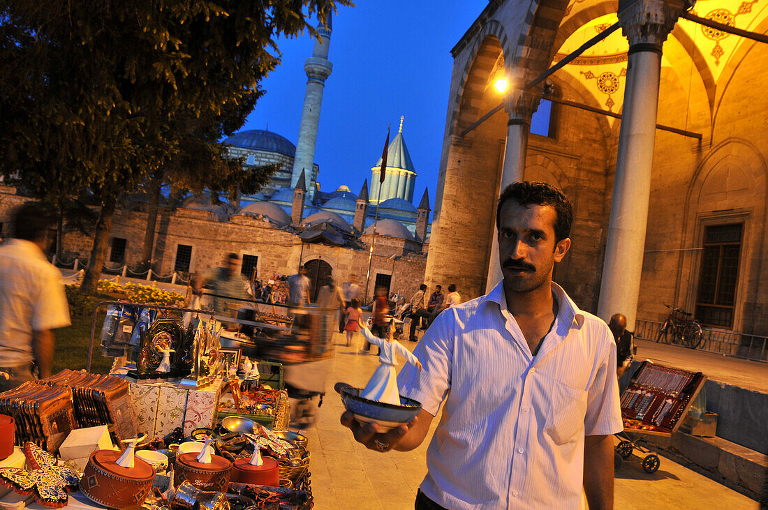 Seller shows a small statuette of Dervish near the Yusufaga Mosque and Mevlana Takkesi, Konya, Anatolia, Turkey