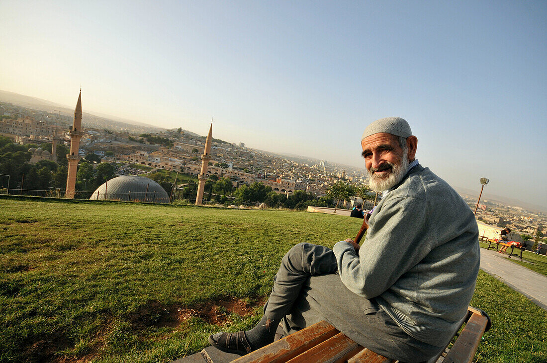 Älterer Mann sitzt auf Bank, Blick auf Sanliurfa, Südost-Anatolien, Türkei