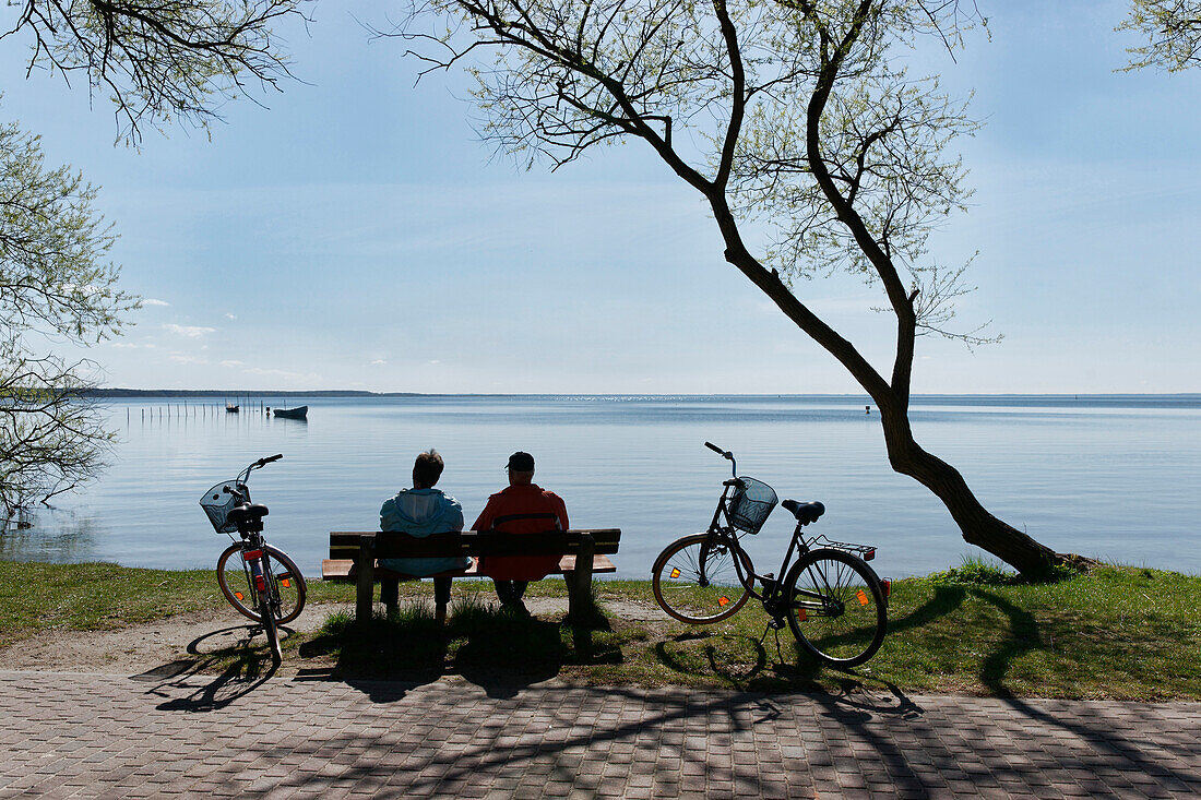 Couple having a rest along the lake shore, Klink, Mueritz, Mecklenburg lake District, Mecklenburg-Western Pomerania, Germany
