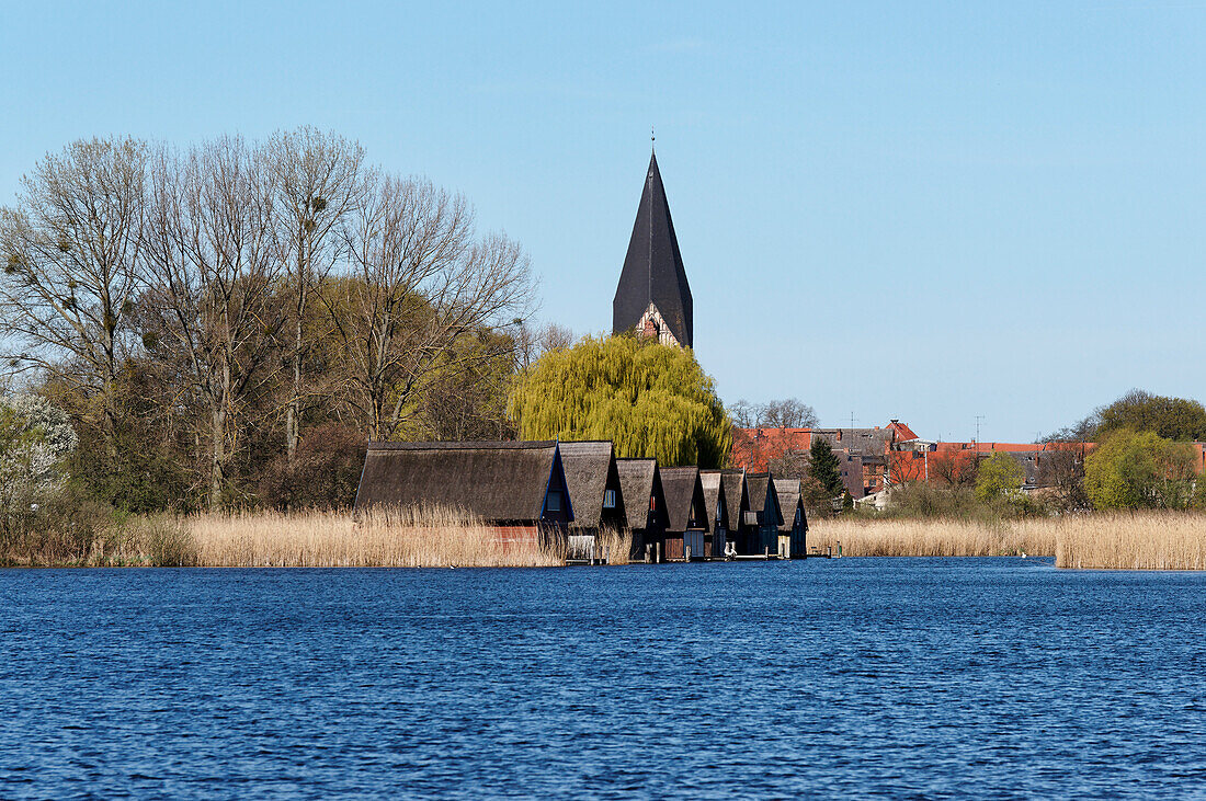 Boathouses and the tower of St. Nicholas church in Große Wünnow in Roebel, Mecklenburg lake District, Mecklenburg-Western Pomerania, Germany