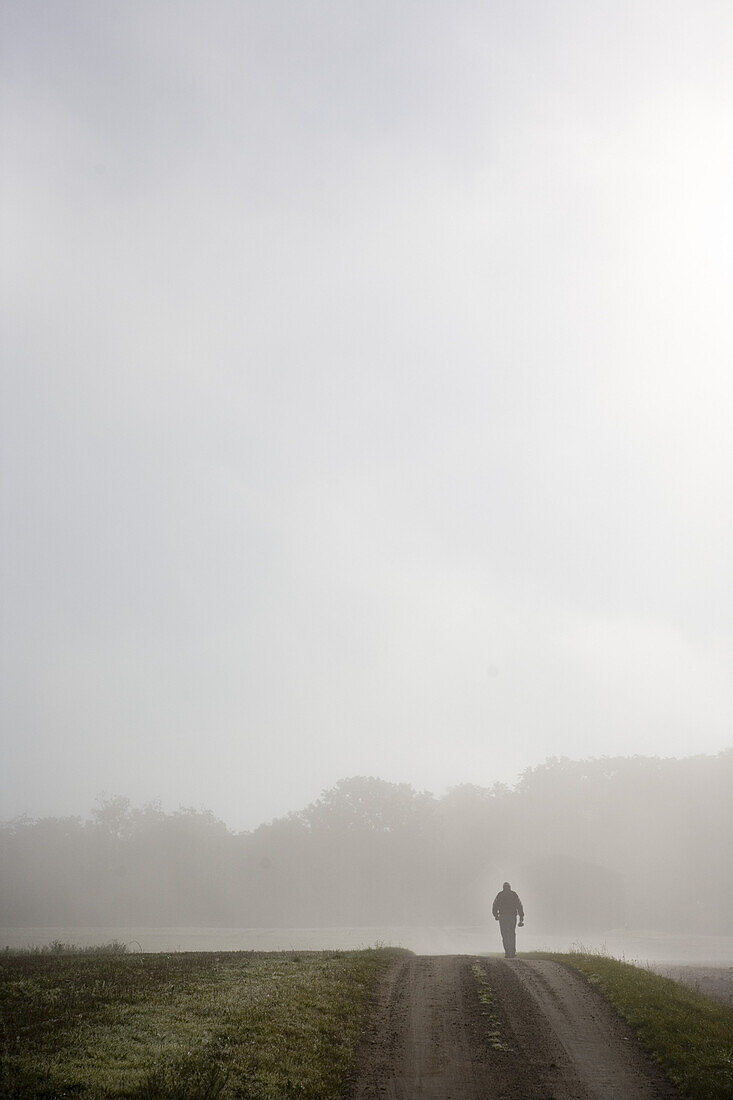 Man on a country road in the fog