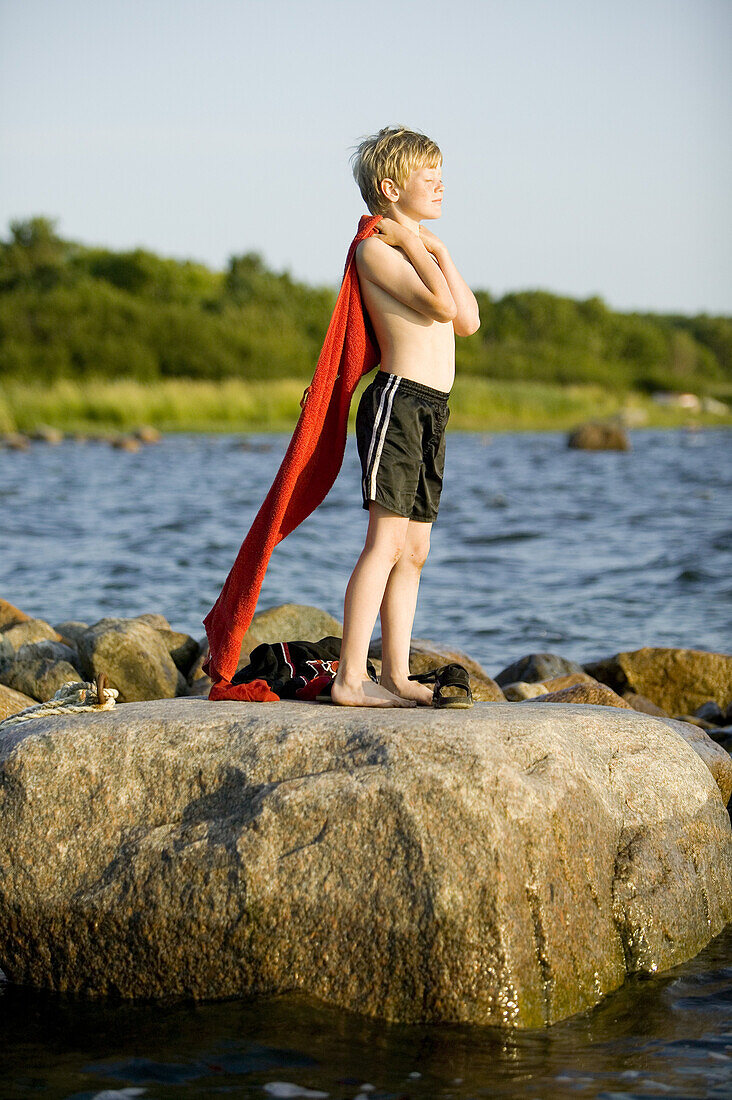 Boy is sitting on a stone in water