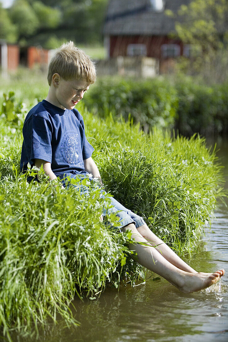 Boy is splashing with his feet in a stream